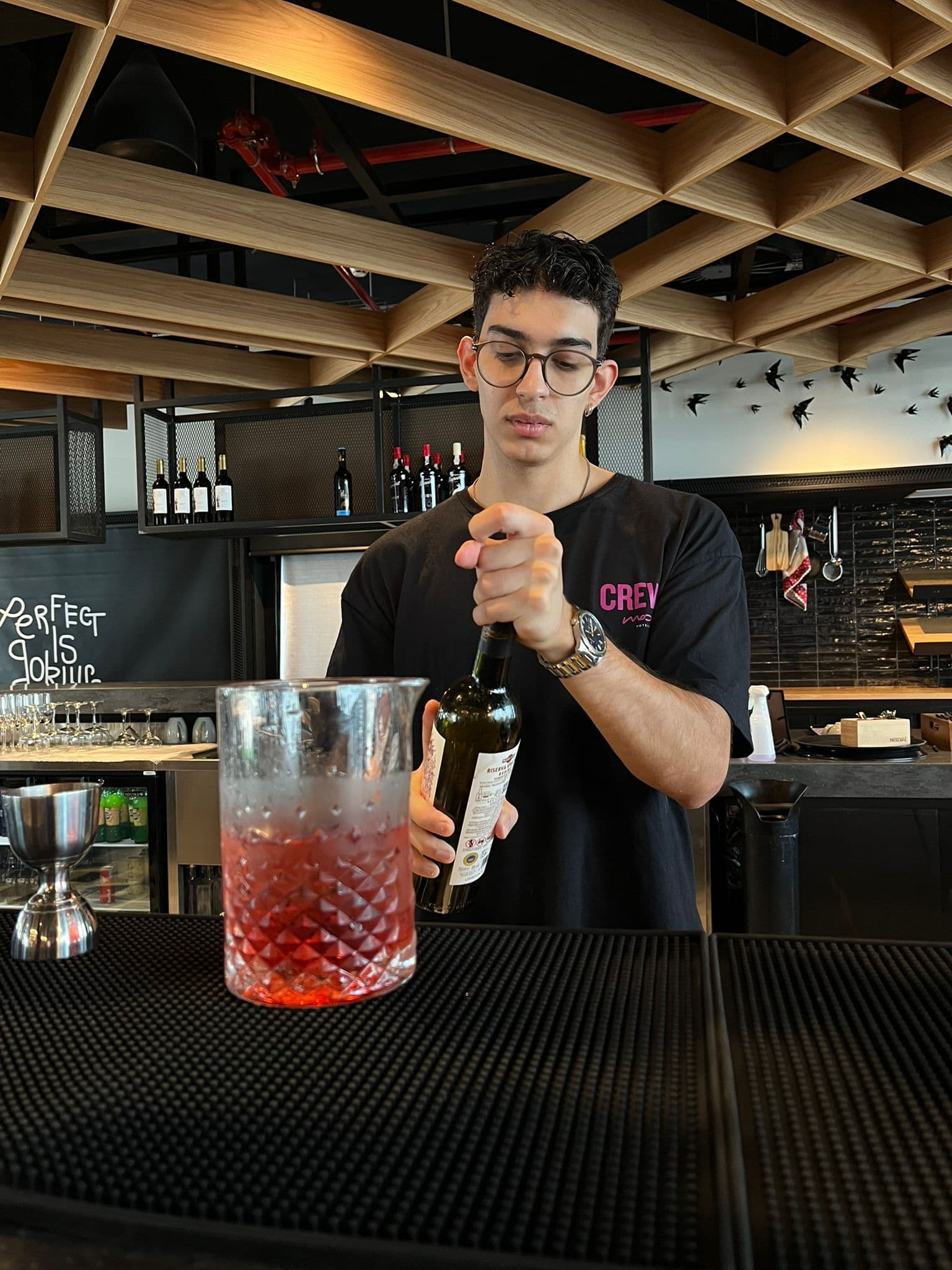 Bartender a abrir uma garrafa de vermute atrás do bar